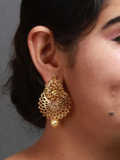 Craftwomanship since Bindhani. A model wears our golden filigree earrings, which are part of a beautiful set with a matching maang tika.