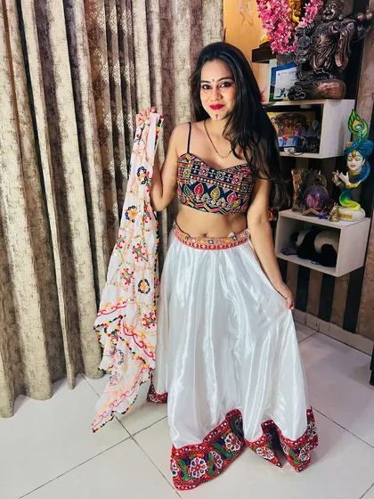 A model showcasing the white satin Garba lehenga, holding up the intricately printed dupatta to display its design.