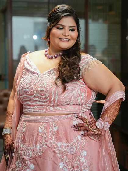 A three-quarter shot of the bride, highlighting her intricate henna and the details of her outfit.