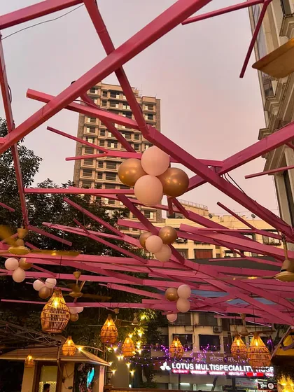 An outdoor view of the Godh Bharai venue, where we installed a pink structural ceiling element decorated with balloon clusters and hanging bamboo lanterns to extend the festive ambiance.