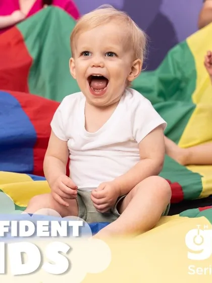 We build confident kids, starting from the very beginning. The pure joy on this baby's face during a group parachute game shows how our activities foster security and self-assurance.