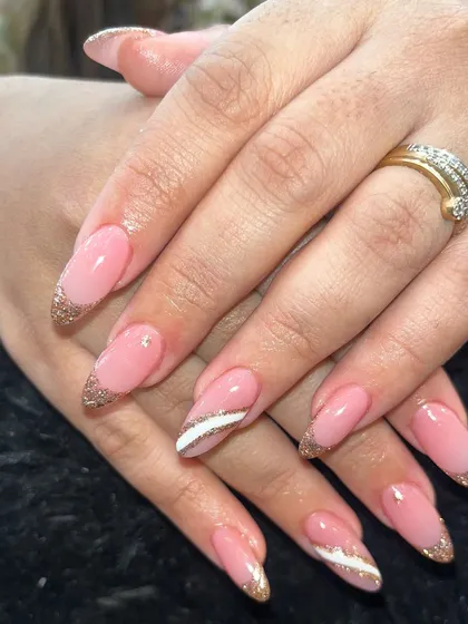 A soft pink base with glittery gold French tips and a single white accent stripe for a touch of modern elegance.