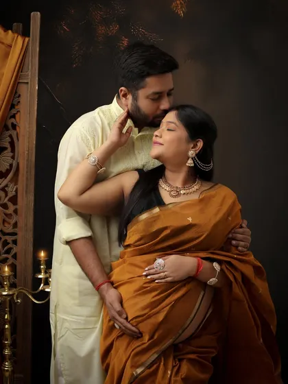 A tender moment between partners, captured in beautiful traditional attire. The mustard saree and light-colored kurta create a warm and harmonious color palette.