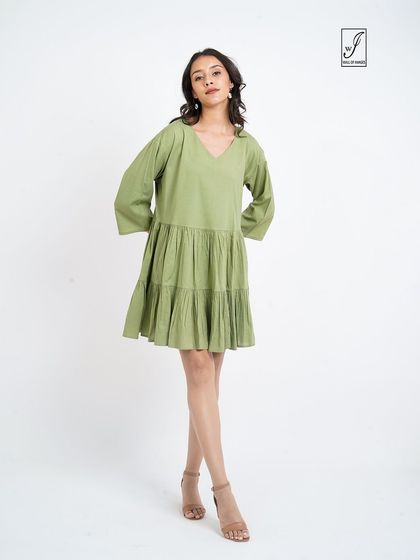 A simple standing pose that clearly shows the v-neck and tiered design of the dress.