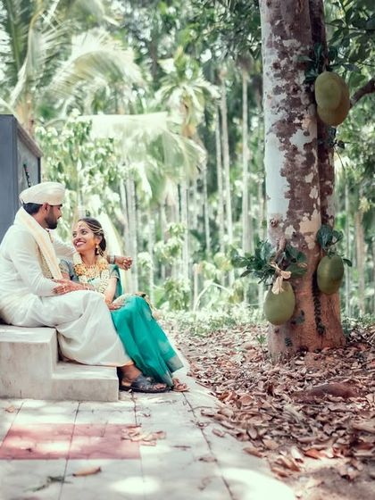 A peaceful portrait of a couple in traditional attire, sitting on steps in a serene, green environment.