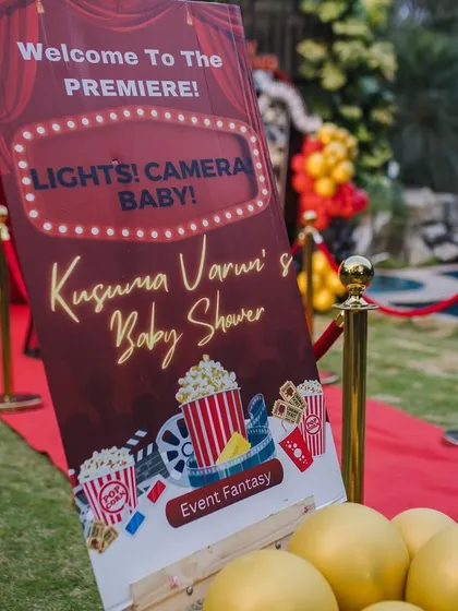 "Welcome to the Premiere!" This custom sign for the movie-themed baby shower immediately immerses guests in the fun 'Lights! Camera! Baby!' concept, complete with popcorn and film reel graphics.