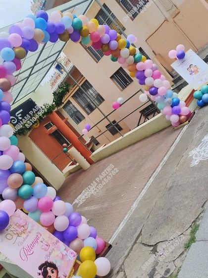 An outdoor balloon arch in pastel colors leading up to an event.