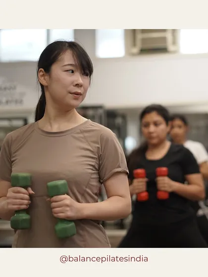 A close-up of a client's focused expression while using light dumbbells. This captures the concentration that Pilates requires.