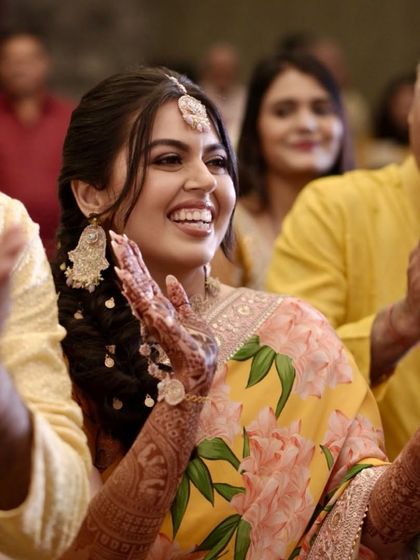 Candid moments from the Haldi ceremony. The makeup is designed to look fresh and beautiful from every angle, even in action.
