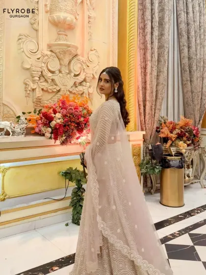 A side profile showcasing the delicate net dupatta and the intricate circular embroidery of this beautiful beige lehenga. It's all in the details.