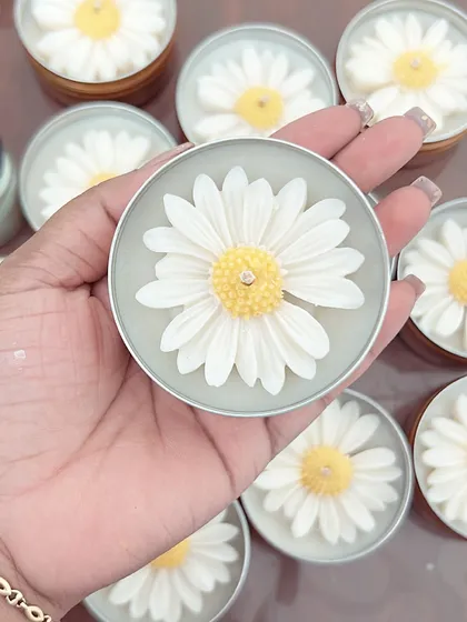 Holding up one of the daisy tin candles. The wax flower inside is a delightful surprise when you open the lid.