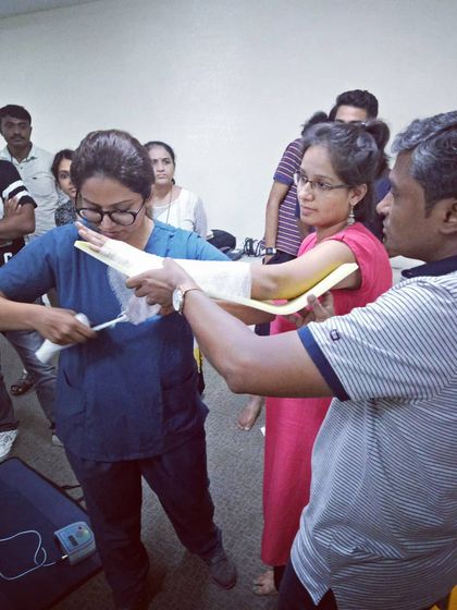 A doctor guides a student through the process of creating a makeshift splint, a common scenario in the wilderness.