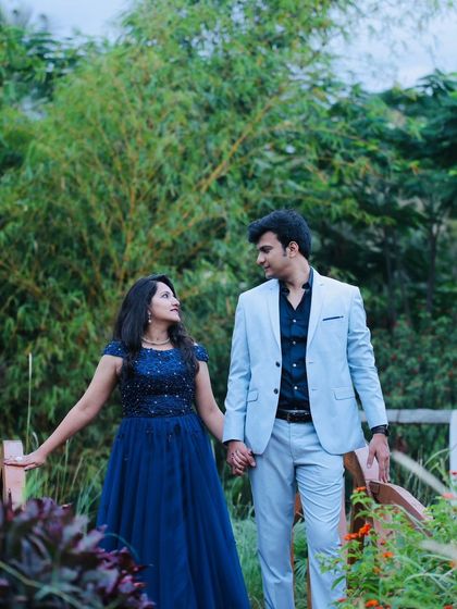 A candid moment between a couple during their outdoor pre-wedding shoot. The navy blue beaded gown adds a touch of sparkle to the romantic setting.