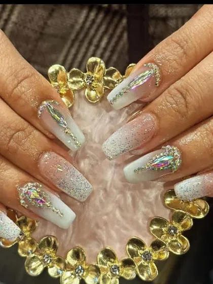 An icy, glamorous look with a white glitter ombre on long coffin nails, featuring large, iridescent multi-faceted crystals as statement pieces.