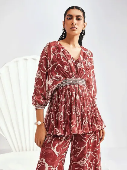 The ELIZA Sharara Set offers a pleated kurta with an embellished waistband and a flared kali sharara with an ornamented border.