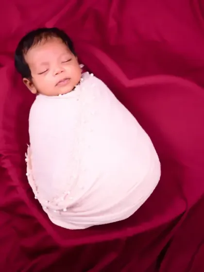 A perfectly swaddled newborn in a heart-shaped space on a rich red fabric. This simple yet powerful image symbolizes the love surrounding a new baby.