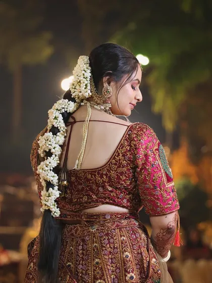 A real bride wearing a long, traditional braid adorned with fresh jasmine flowers. This hairstyle is perfect for a classic wedding look and is designed to stay in place throughout the festivities.