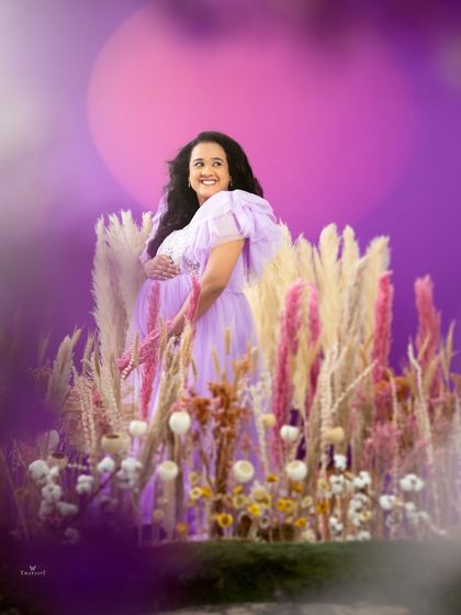 A joyful and vibrant portrait in a field of lavender-hued flowers. The mom-to-be's happy expression and the colorful setting create a feeling of pure bliss.