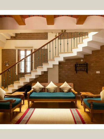 A frontal view of the living area, showing the harmony between the wooden furniture, exposed brick, and the clean lines of the staircase.