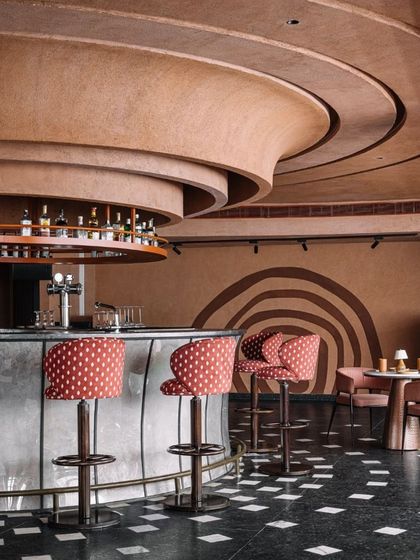 The curved bar and ceiling details at Idylll create a fluid, organic feel. The polka-dot upholstery adds a playful touch to the otherwise earthy and monolithic design.
