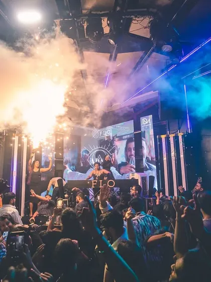 The crowd going wild under a cloud of smoke and lights.