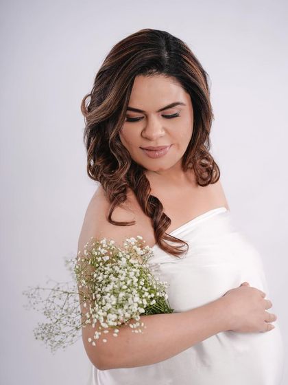 A simple and pure solo portrait with a white drape and a bouquet of baby's breath, creating a soft and angelic look.