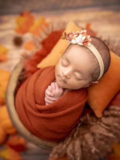 A close-up of a smiling newborn in our autumn pumpkin patch setup. That little smile is just everything.