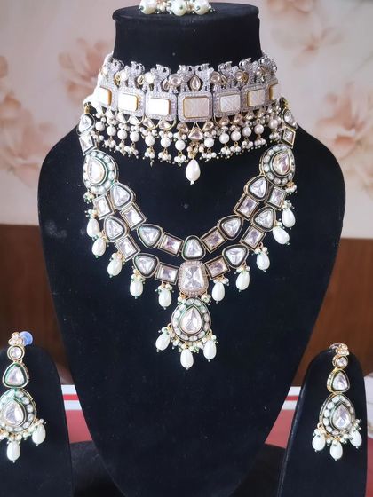 A layered bridal set combining a white choker with a longer Polki necklace, available for rent.