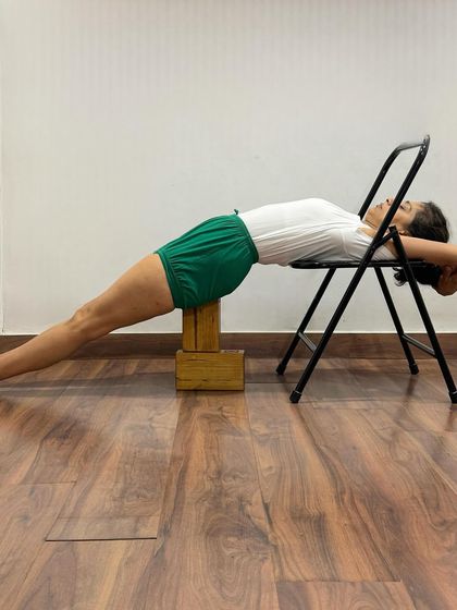 This Purvottanasana setup with a chair and blocks supports the pelvis and head. It allows for a focus on leg extension and chest opening without bearing full weight on the arms and wrists.