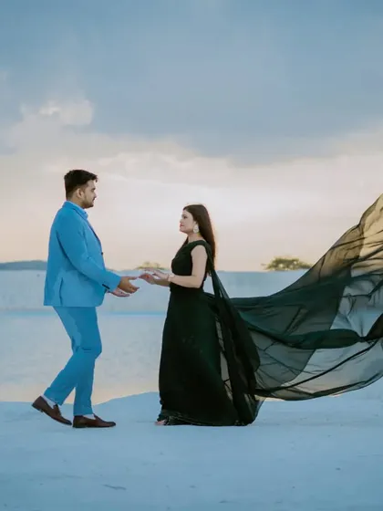 A beautifully composed shot of the couple about to meet, with the bride's gown flowing dramatically. The cloudy sky adds a moody and atmospheric feel to the image.