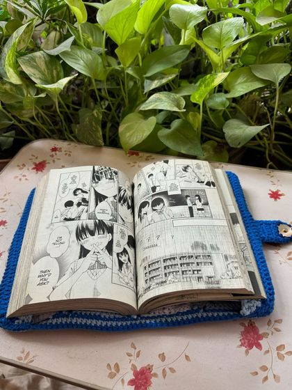 The book cover shown open, protecting a manga. It's a great way to keep your books in perfect condition.