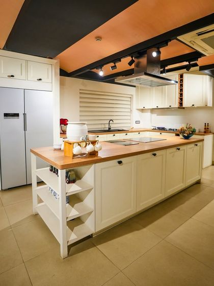 The Ravenna White country-style kitchen on display in our Kolkata showroom, featuring a large island with a wooden countertop and open shelving.