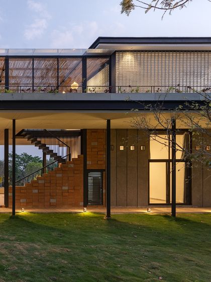 The combination of materials is clearly visible here: warm CSEB bricks for the staircase, cool granite-clad walls, and translucent glass blocks on the upper level. This textural variety is a key part of the project's design language.