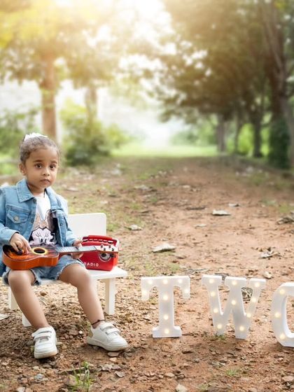 An outdoor second birthday shoot with a cool, retro vibe, featuring a toddler with a ukulele and a vintage-style radio.