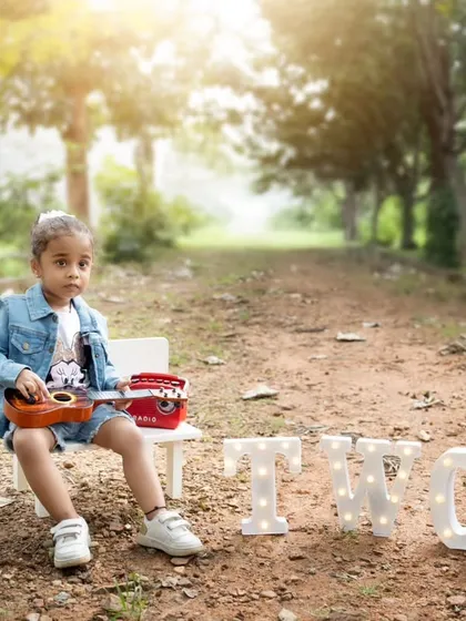 An outdoor second birthday shoot with a cool, retro vibe, featuring a toddler with a ukulele and a vintage-style radio.