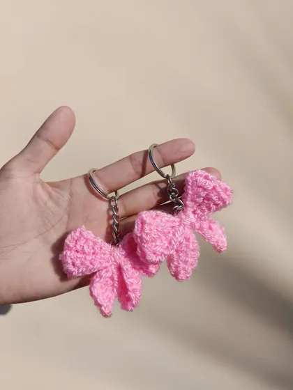 A close-up of two pink bow keychains. The textured stitch I use gives them a unique and high-quality feel.
