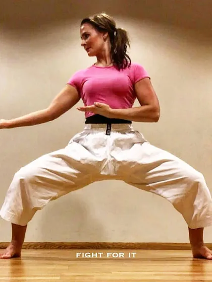 A student holds a strong horse stance (Shiko-dachi), a fundamental position in karate for developing lower body strength and stability. Proper form is the base for all powerful movements.