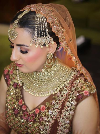A traditional bridal look featuring elaborate jewellery. The makeup is focused on defined eyes and a flawless base to complement the heavy adornments.