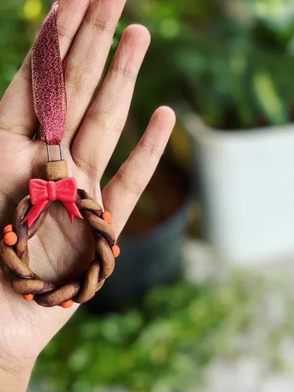 A handmade ceramic wreath ornament, complete with a little red bow. These small, detailed pieces are a joy to make.