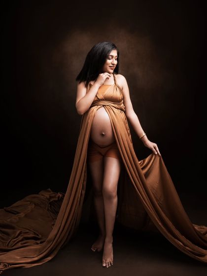 A goddess in her own right. This portrait captures her silhouette, strength, and story in a flowing golden-brown fabric drape.