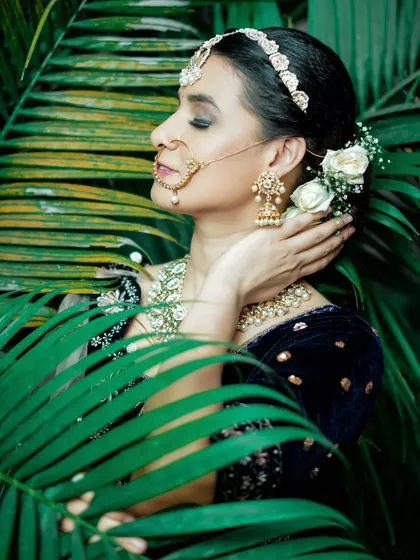 A serene and artistic portrait of the bride. Her classic makeup and hairstyle with white roses create a look of timeless beauty.