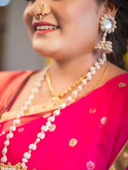 A detailed close-up of a bride's traditional Maharashtrian jewelry. The focus is on her unique seed-based necklace and earrings, showcasing the intricate and meaningful accessories of a cultural wedding.