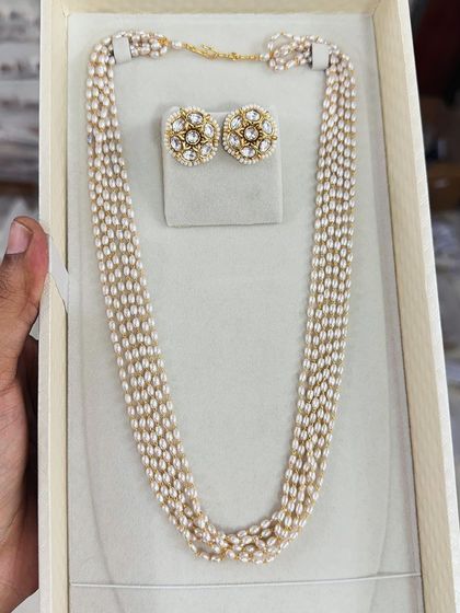 This multi-strand pearl necklace is paired with kundan-style stud earrings for a classic and royal look. It's a versatile set that can be dressed up or down.