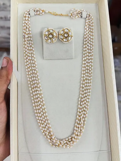 This multi-strand pearl necklace is paired with kundan-style stud earrings for a classic and royal look. It's a versatile set that can be dressed up or down.