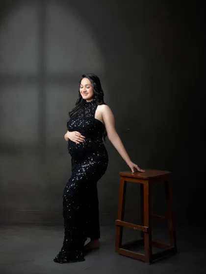 Simple elegance in a full-length black sequin gown. This portrait uses subtle lighting to highlight the beautiful silhouette of the mother and her baby bump.