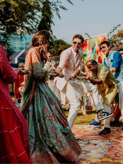 A fun-filled moment from the wedding festivities, showing the couple and their guests engaged in a playful game of tug-of-war.