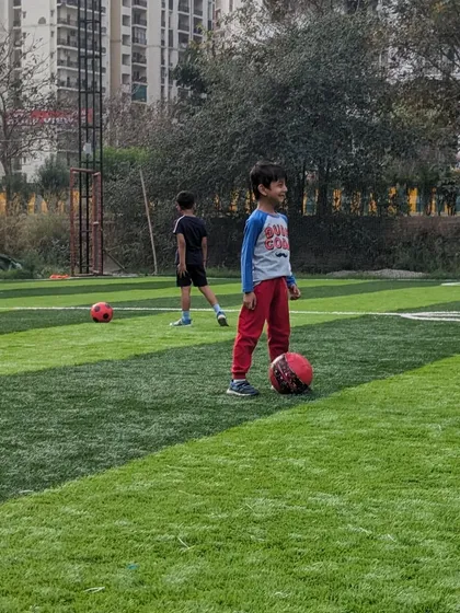 A young player takes a moment during a drill, happy to have a football at his feet on the training ground.
