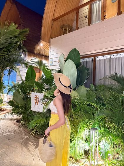 My Goa vacation look. A white crochet top, yellow pants, and a straw bag and hat, posing outside our beautiful resort villa.