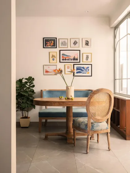 A full view of the cozy dining area. The wooden table adds warmth, while the blue upholstery on the bench and chair ties in with the color palette of the adjacent living room.