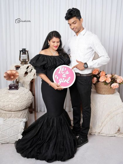 A gender reveal shot in our studio, with the couple holding a sign that says "It's a girl!".